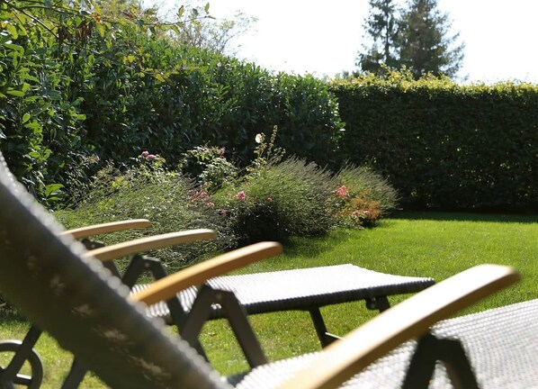 A garden with a lawn, a hedge, and a picnic table.