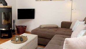 Una sala de estar con un sofá, un televisor, una chimenea y un cuadro en la pared.