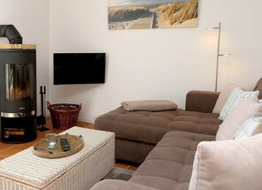 Ein Wohnzimmer mit einer Couch, einem Fernseher, einem Kamin und einem Gemälde an der Wand.