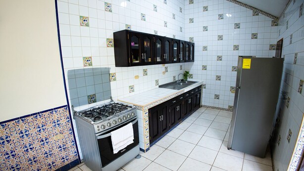 A kitchen with a gas stove, oven, cabinets, and a refrigerator.