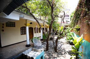 A courtyard with a white building, a hanging chair, and potted plants.