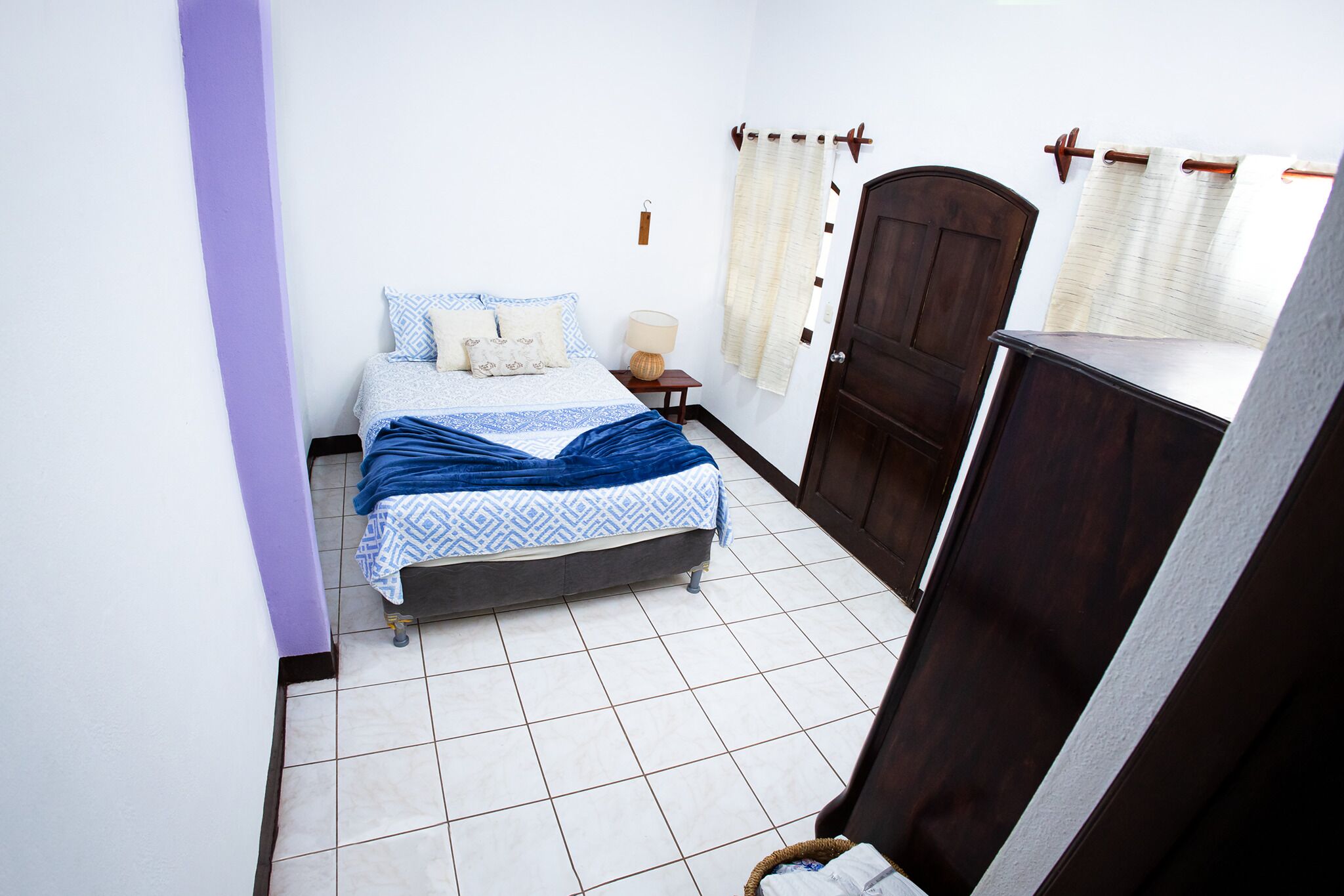 A bedroom with a bed, a nightstand, a dresser, and a door.