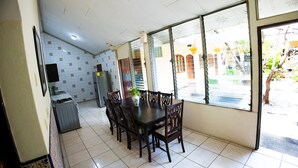 A dining area with a table and chairs, a refrigerator, and a tiled floor.