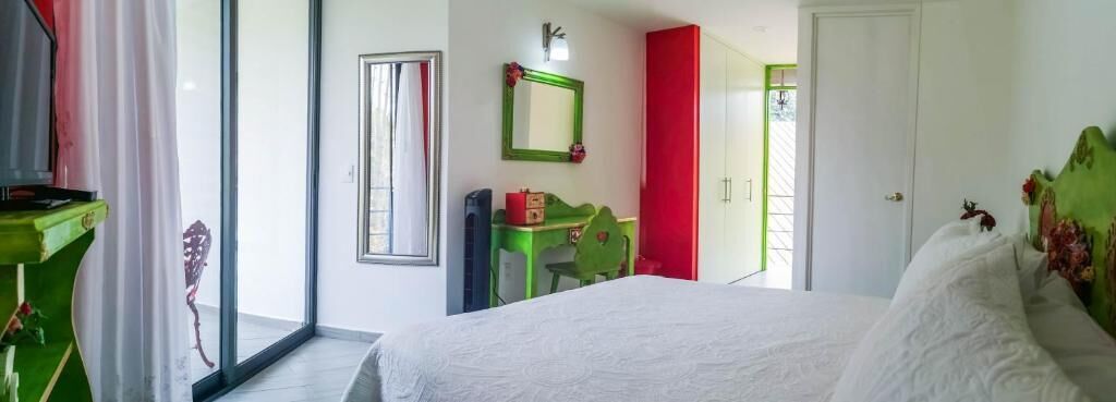 Une chambre à coucher comprenant un lit, un bureau, une chaise, un miroir et une armoire.