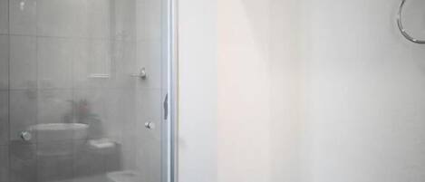 A bathroom with a glass shower enclosure, a toilet, and a sink.