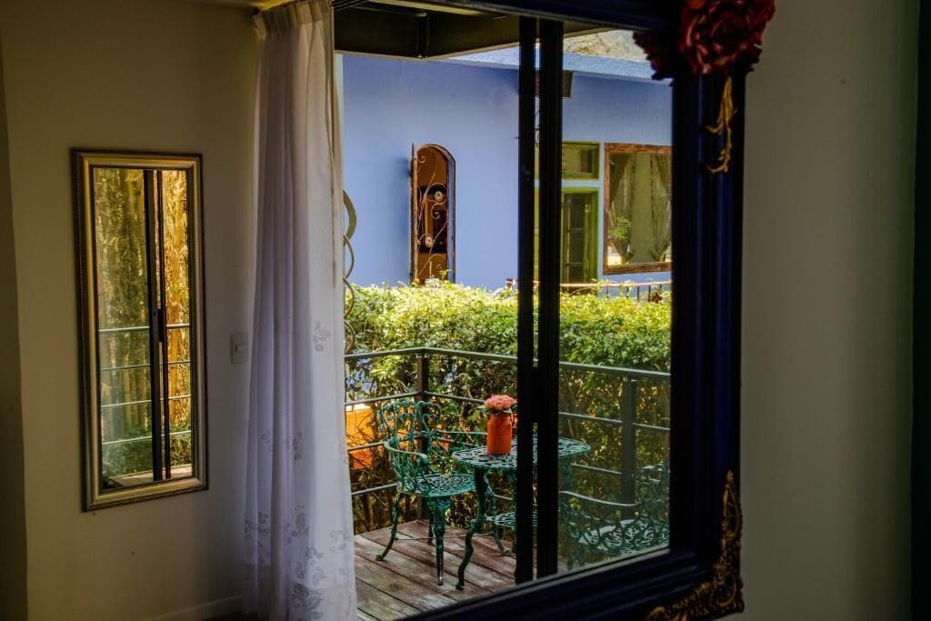 A room with a view of a balcony, a window with curtains, and a door with a mirror.