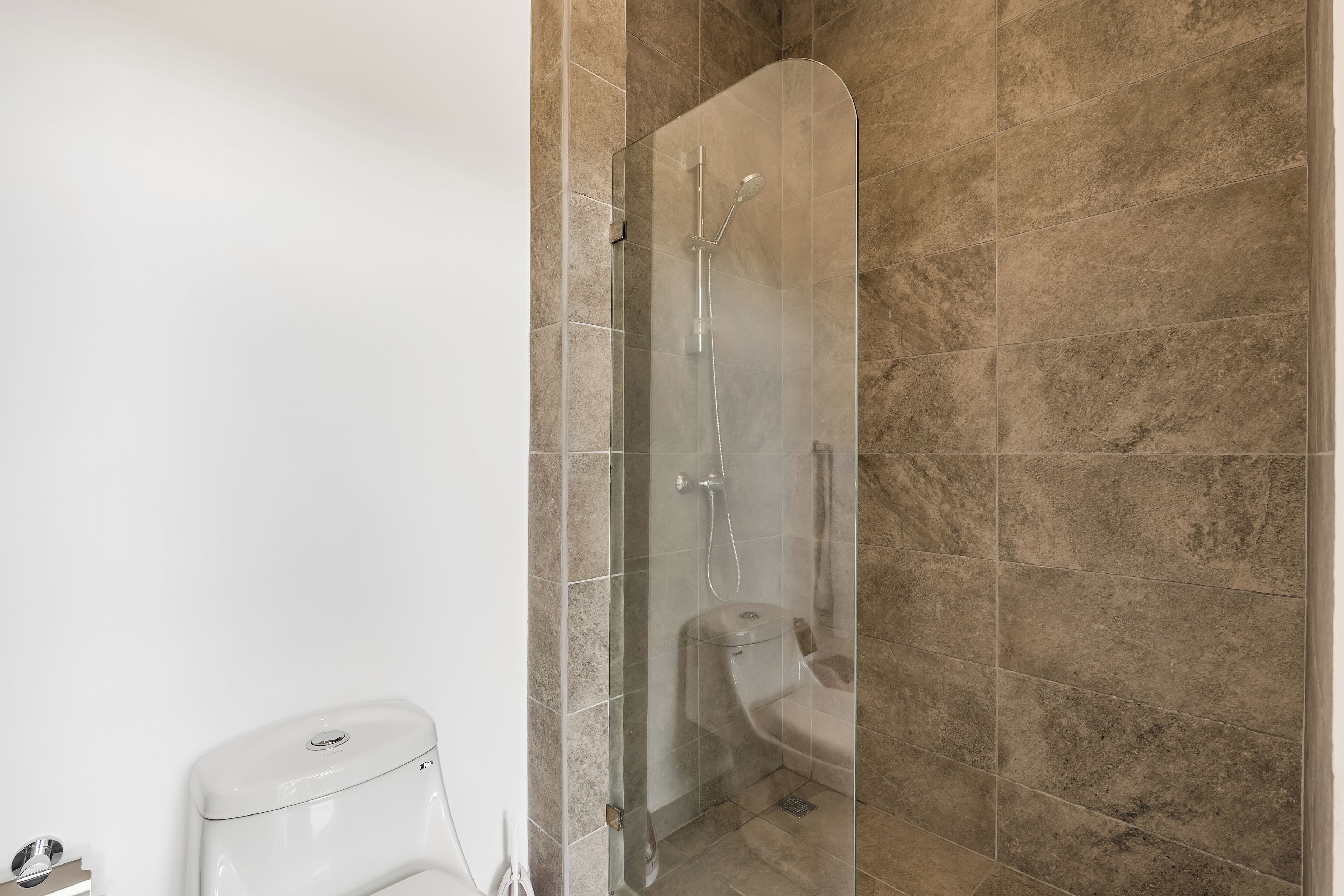 A bathroom with a glass-enclosed shower, a toilet, and a white pedestal sink.