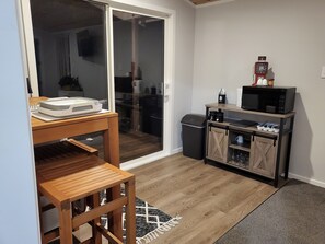 A compact kitchen with a microwave, coffee maker, and a small cabinet.