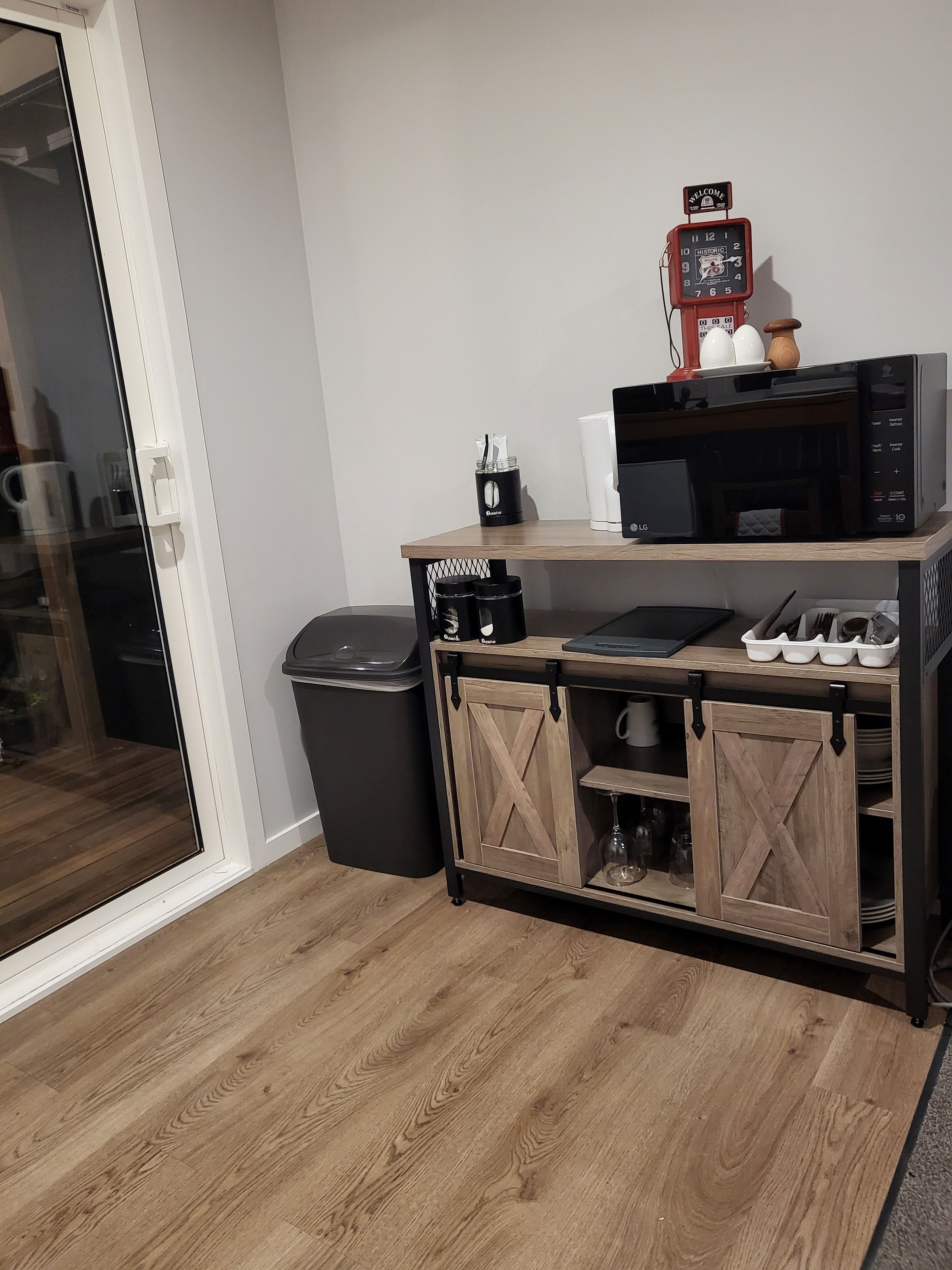 A kitchenette with a microwave, coffee maker, and a small cabinet with storage.
