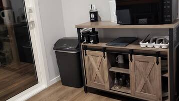 A kitchenette with a microwave, coffee maker, and a small cabinet with storage.