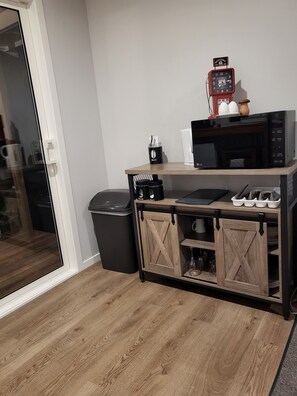 A kitchenette with a microwave, coffee maker, and a small cabinet with storage.