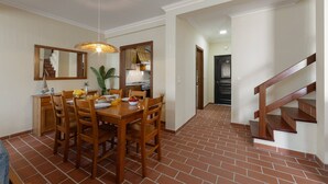 A dining area with a wooden table, chairs, and a hanging light fixture. - Jardim da Lagoa - Rustic Retreat (Óbidos)