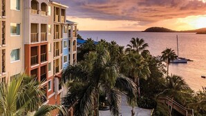 A multi-story hotel with balconies, a view of the sea, and palm trees. - St. Thomas 3 Bedroom Villa at Resort w/Amenities (St Thomas)