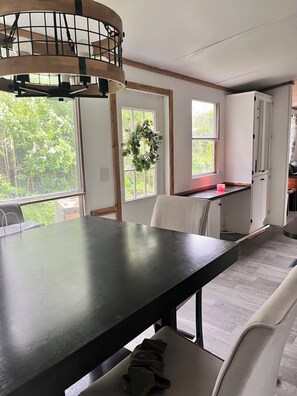 A modern kitchen with a dark countertop, white cabinetry, and a hanging light fixture.