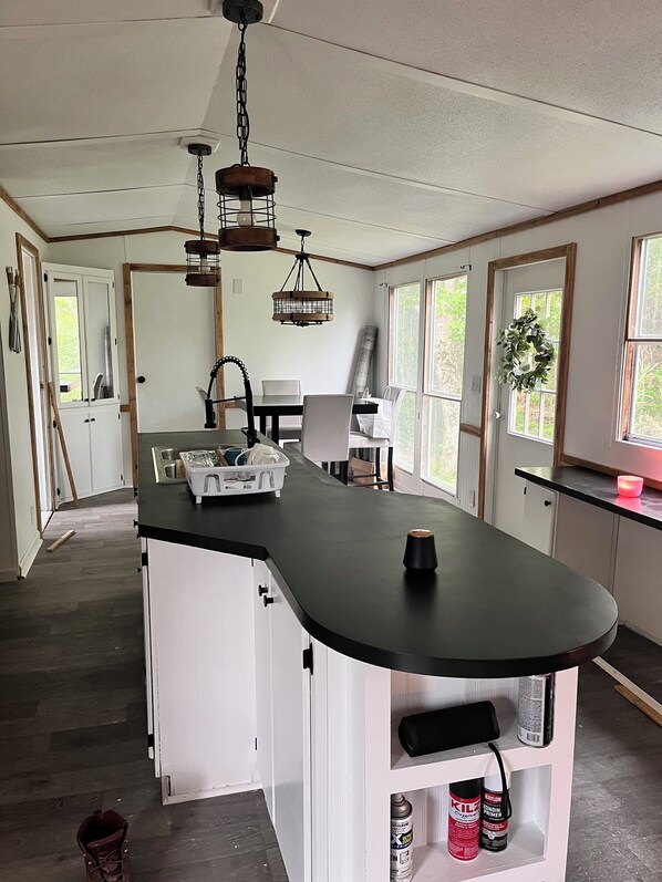 A kitchen with a curved countertop, white cabinetry, and a hanging light fixture.