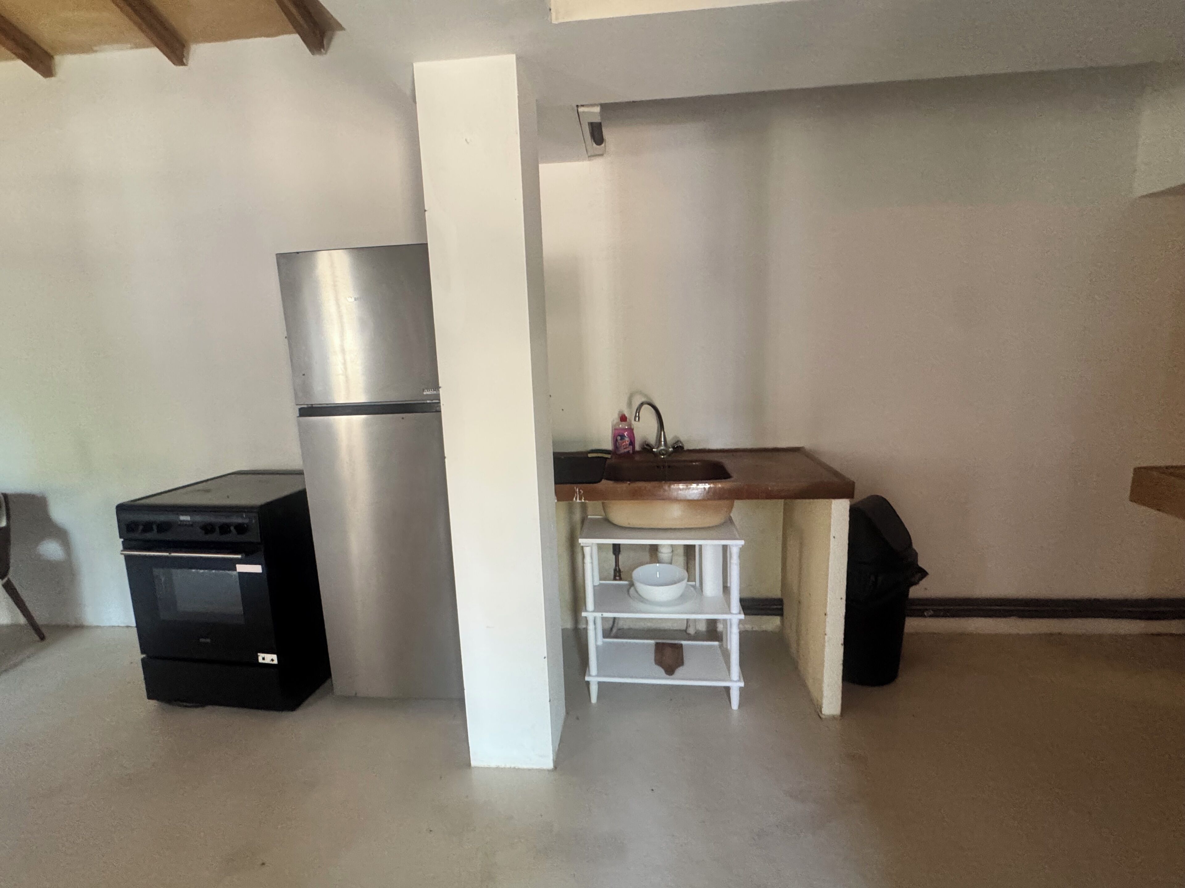 A compact kitchen with a refrigerator, oven, and a sink with a small countertop.