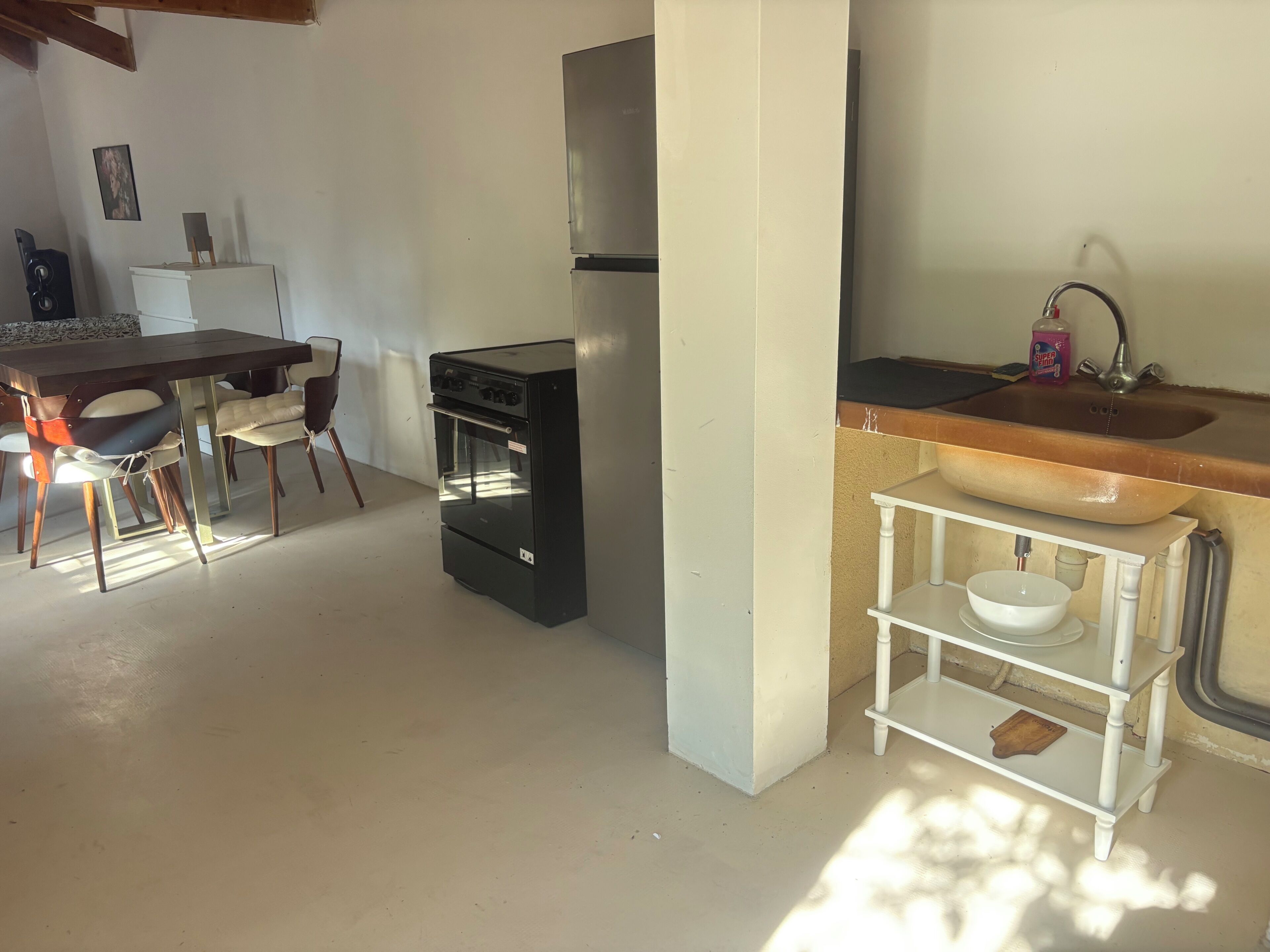 A compact kitchen with a built-in oven, a sink, and a small dining area with chairs.