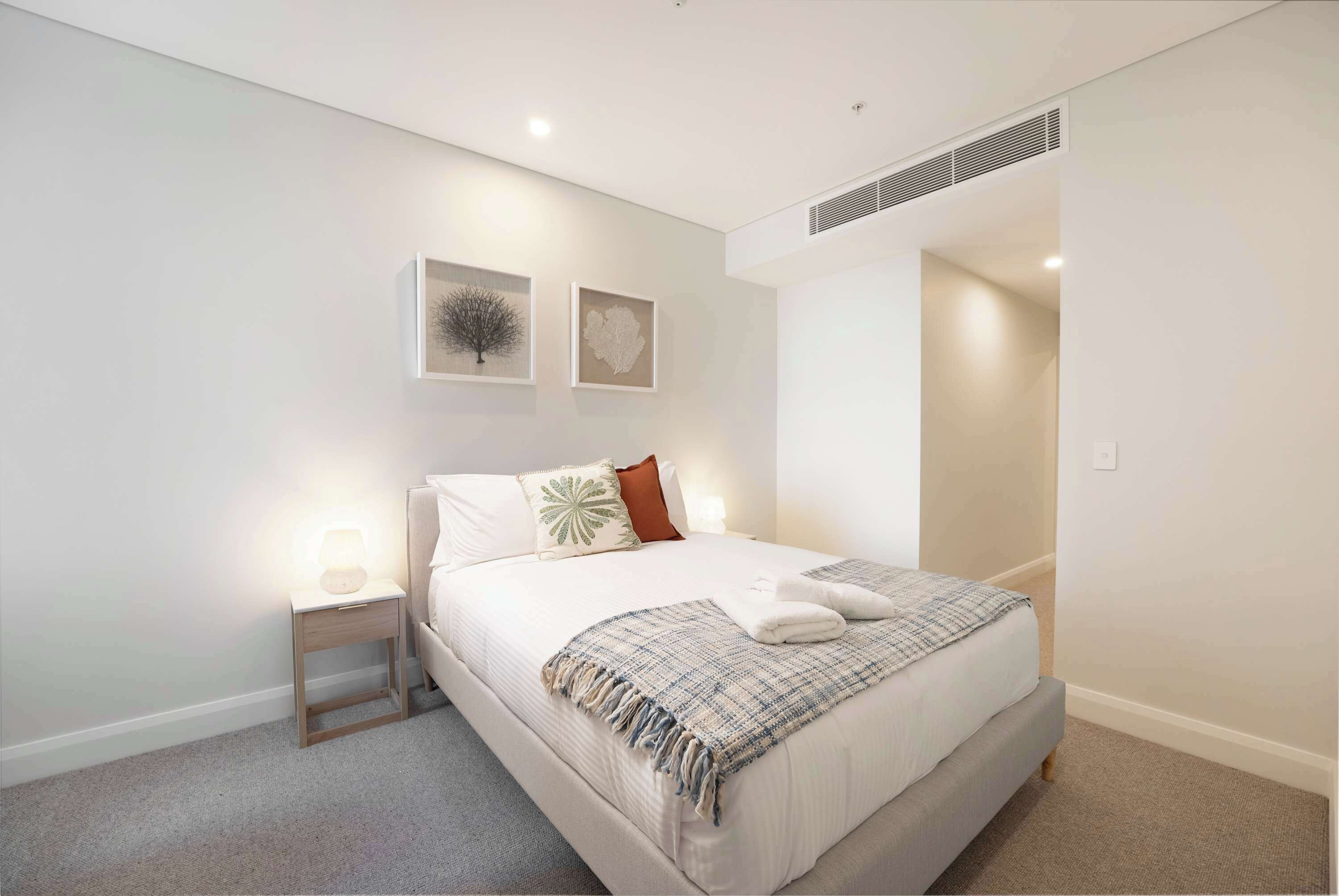 A modern bedroom with a bed, nightstand, and wall art.