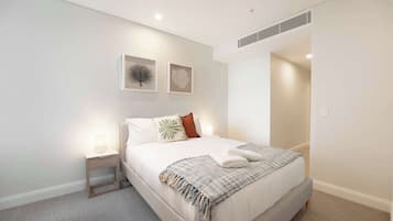 A modern bedroom with a bed, nightstand, and wall art.