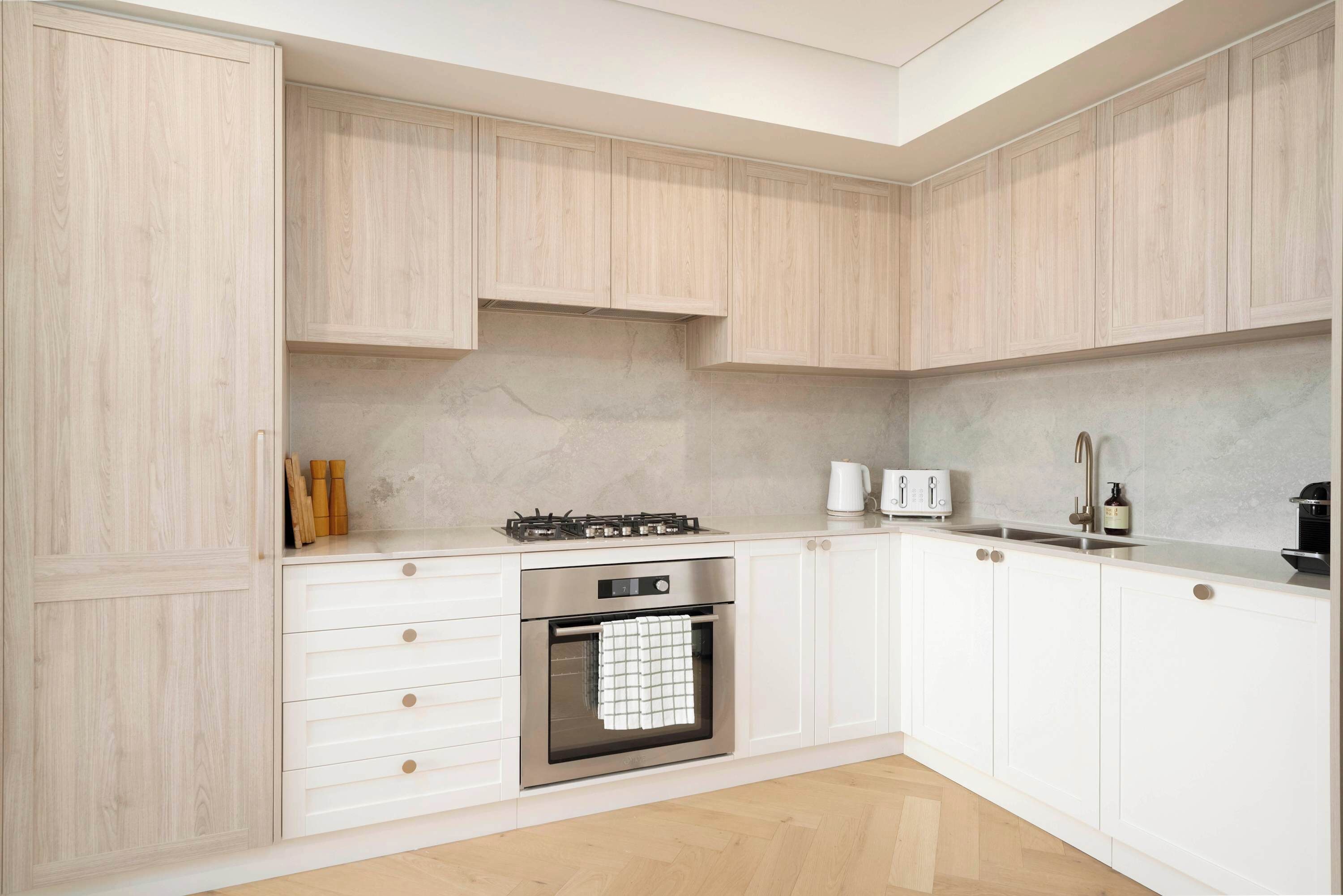 A modern kitchen with white cabinetry, a built-in oven, a gas stove, and a stainless steel sink.