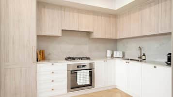 A modern kitchen with white cabinetry, a built-in oven, a gas stove, and a stainless steel sink.