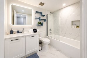 A modern bathroom with a white vanity, a large mirror, a shower enclosure, and marble flooring. - Coastal Oasis • Sleeps 11 • Rooftop + Pool • Beach (Hollywood)