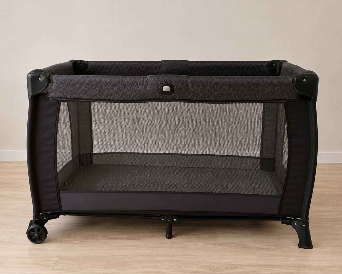 Un parc pour bébé noir, doté de roulettes et d’un dessus en tissu à mailles, posé sur un plancher en bois.