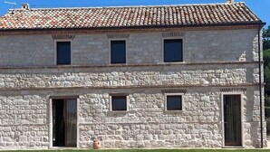 A stone building with a tiled roof, multiple windows, and a door. - Pietra Museum Suites Sirolo (Sirolo)