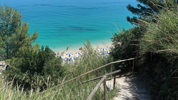 A coastal path leading to a beach with clear waters and a few umbrellas. - Pietra Museum Suites Sirolo (Sirolo)