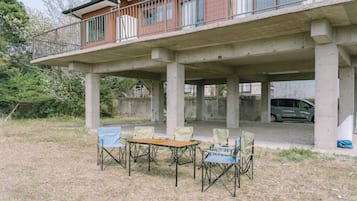 A building with a balcony, concrete pillars, and a table with chairs.