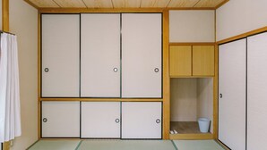 Ett traditionellt japanskt rum med tatamimattor på golvet, skjutdörrar och en liten förvaringsplats med en hink.