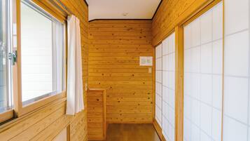 A narrow hallway with wooden walls and a wooden floor, leading to a sliding door on the right.