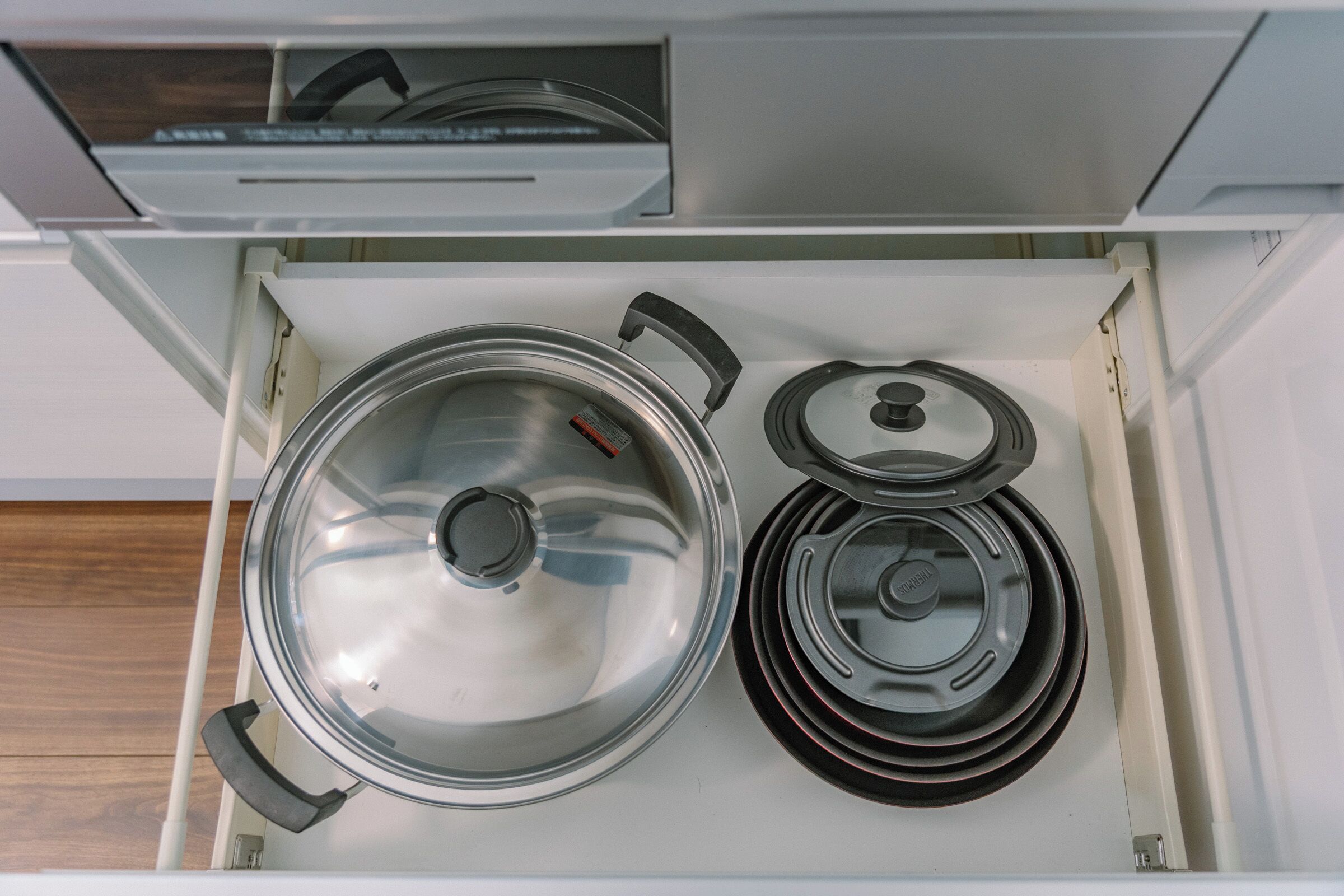 A kitchen drawer with a stove, pots, and a kettle.