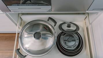 A kitchen drawer with a stove, pots, and a kettle.