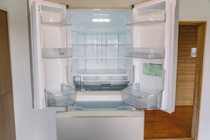 An open refrigerator with clear plastic shelves and a freezer compartment.