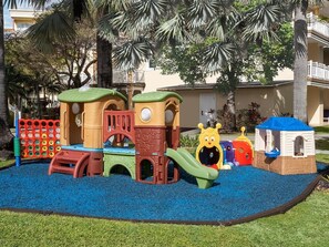 Ein Spielplatz mit Klettergerüsten, Rutschen und einer kleinen Spielhütte.