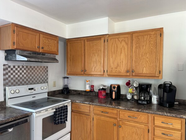 A kitchen with wooden cabinets, a stove, a coffee maker, and a blender.