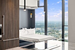 Ein modernes Hotelzimmer mit Bett, Blick auf die Stadt und einem großen Fenster.