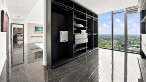 Quarto de hotel moderno com uma janela grande, um guarda-roupa preto e vista para a cidade.