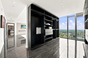 Ein modernes Hotelzimmer mit großem Fenster, einem schwarzen Kleiderschrank und Blick auf die Stadt.