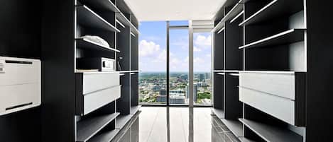 Ein moderner Kleiderschrank mit Einbauregalen und Blick auf eine Stadtlandschaft durch eine Glastür.