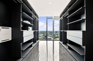 A modern closet with built-in shelving and a view of a cityscape through a glass door. - Luxury Sky Penthouse with Ocean & City Views (Miami)