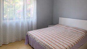 A bedroom with a bed, a window with sheer curtains, and an air conditioning unit on the wall. - A holiday home in a quiet neighborhood 5 minutes walking distance from the sea. (Vlora)