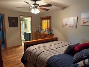 Ein Schlafzimmer mit Bett, Kommode, Spiegel und Deckenventilator.