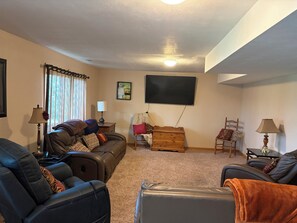A living room with a sofa, chairs, a TV, and a wooden chest of drawers. - Lake home retreat in the heart of Okoboji (Milford)