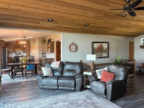 Ein Wohnzimmer mit Kamin, Ledersofas, einem Essbereich und einer Küche im Hintergrund.