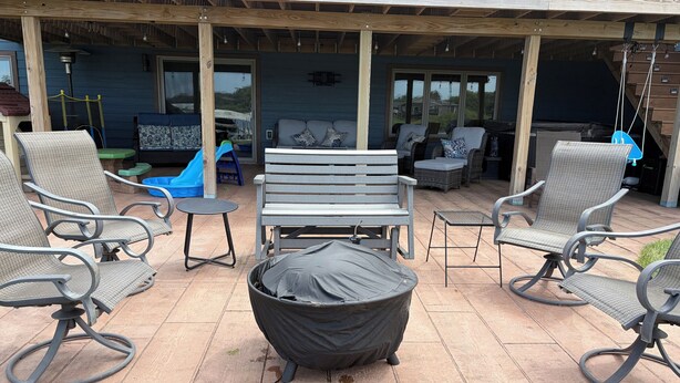 An outdoor patio area with a covered seating area, including a bench and multiple chairs, and a covered fire pit. - Lake home retreat in the heart of Okoboji (Milford)