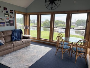 A living room with a large window, a sofa, a coffee table, and a dining area with chairs. - Lake home retreat in the heart of Okoboji (Milford)