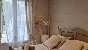 A bedroom with a wooden bed, two pillows, a bedside table, and a window with curtains.