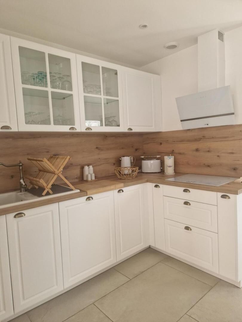 Eine Küche mit weißen Schränken, einer Holz Arbeitsplatte und einem eingebauten Herd.